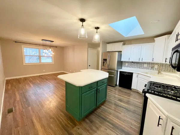 a kitchen with kitchen island wooden floors appliances and cabinets