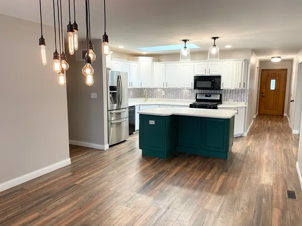 a kitchen with stainless steel appliances a sink dishwasher a refrigerator and a stove with wooden floor