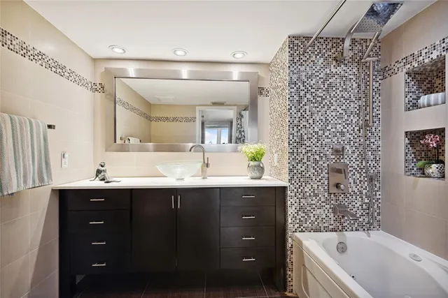 a bathroom with a double vanity sink mirror and bathtub