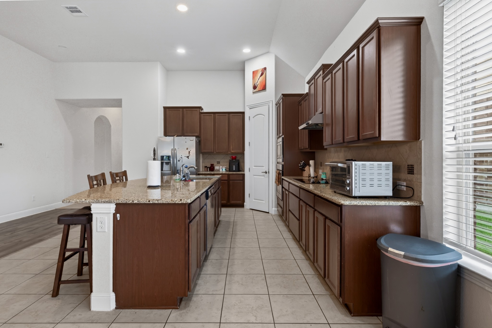 1017 Tabernash Leander, TX 78641 - Photo 11 of 38 Kitchen featuring an expansive central island with stone-finish countertop, dark wood cabinetry, and stainless steel appliances