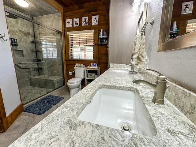 a bathroom with a granite countertop sink a mirror and shower