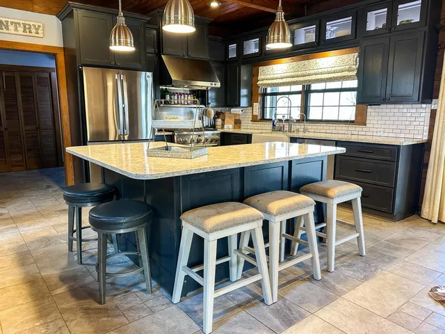 a kitchen with a dining table chairs cabinets and stainless steel appliances