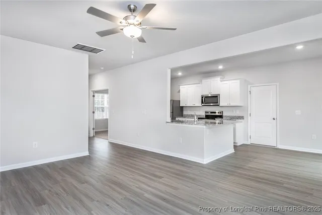 a view of kitchen with stainless steel appliances refrigerator stove and wooden floor