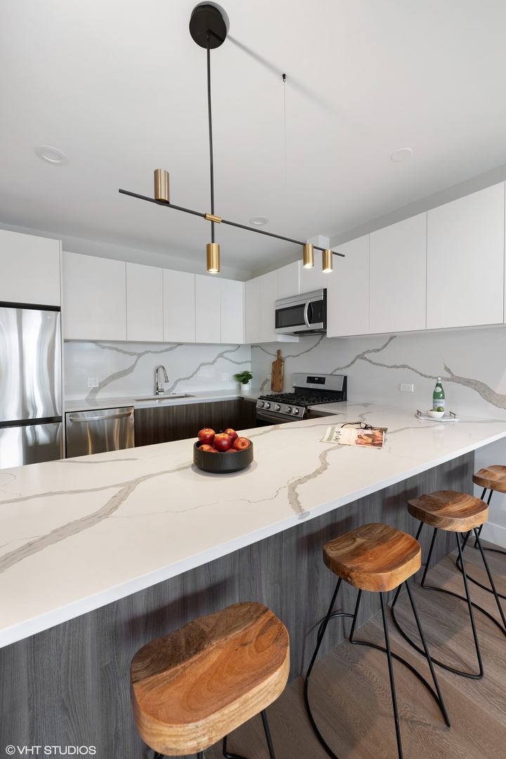 2342 West Adams Street, Unit 505 Chicago, IL 60612 - Photo 6 of 20 a kitchen with a sink a stove and chairs