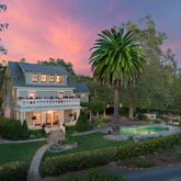 a sign board with a garden and tree in the background