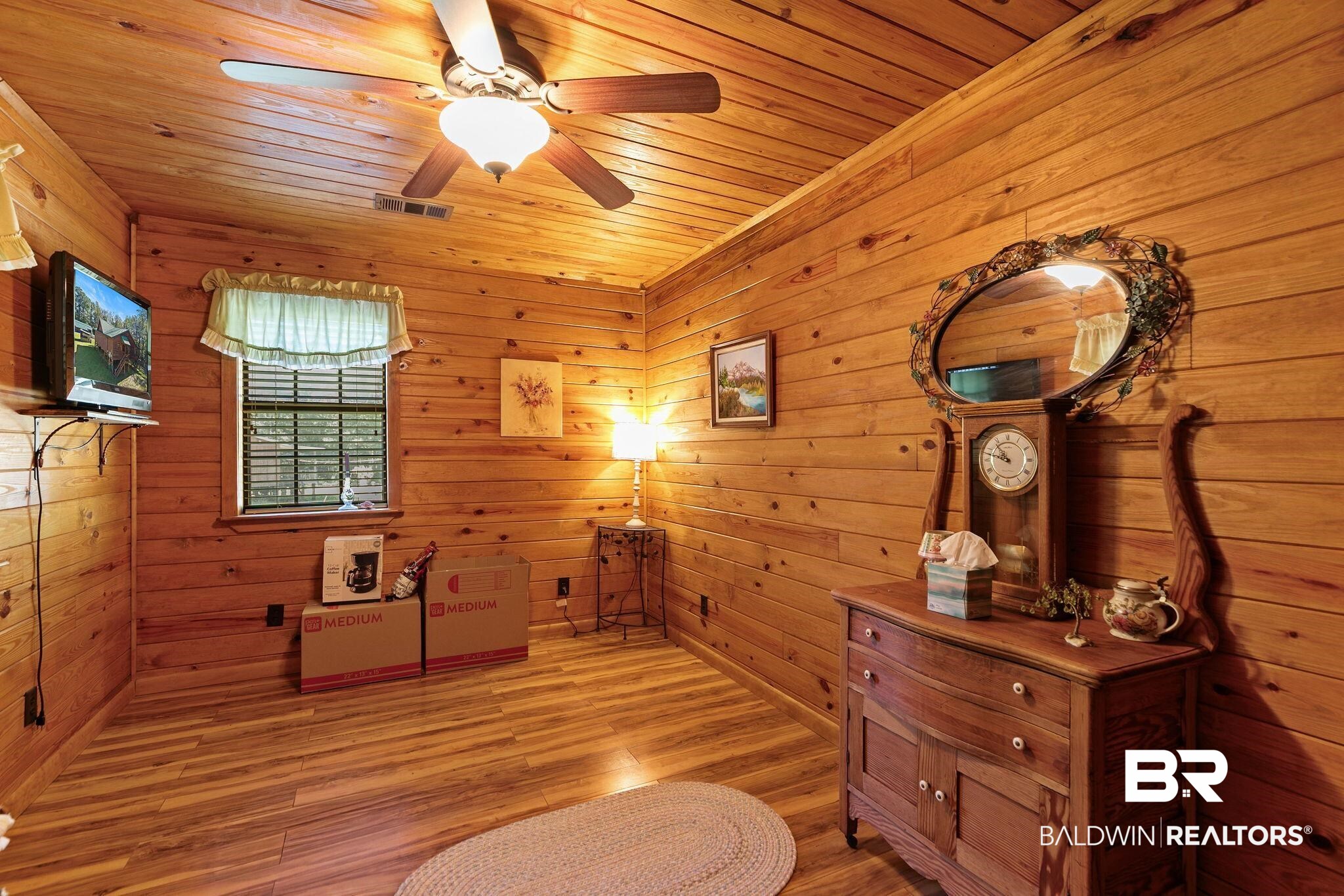724 Rowell Lane Brewton, AL 36426 - Photo 26 of 40 Living area featuring wooden walls, light wood-type flooring, wooden ceiling, and a ceiling fan
