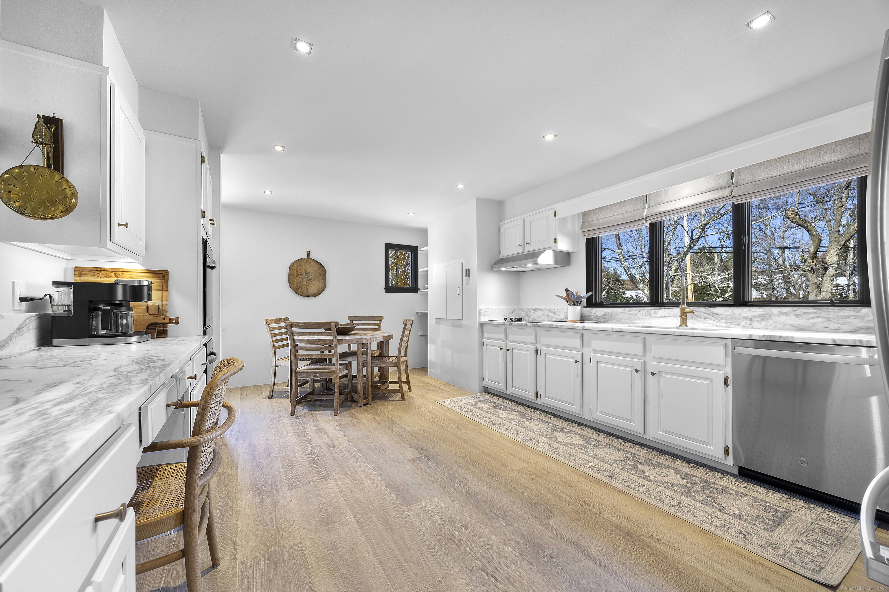 1001 Hulls Farm Road Fairfield, CT 06890 - Photo 14 of 40 a kitchen with stainless steel appliances kitchen island granite countertop a stove a sink a dining table and chairs with wooden floor