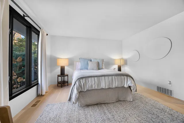 a bedroom with a bed lamp and a large window