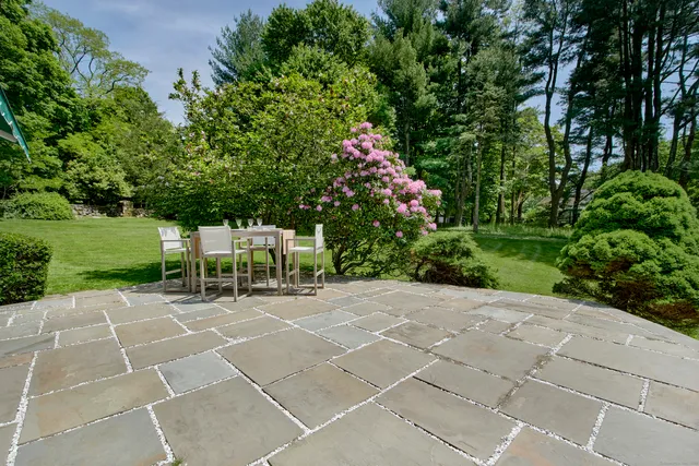 a lawn chairs sitting in a yard with plants and large trees