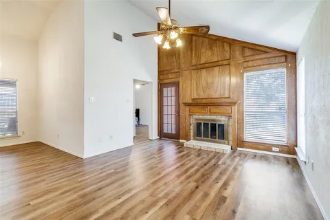 a view of an empty room with wooden floor fireplace and a window