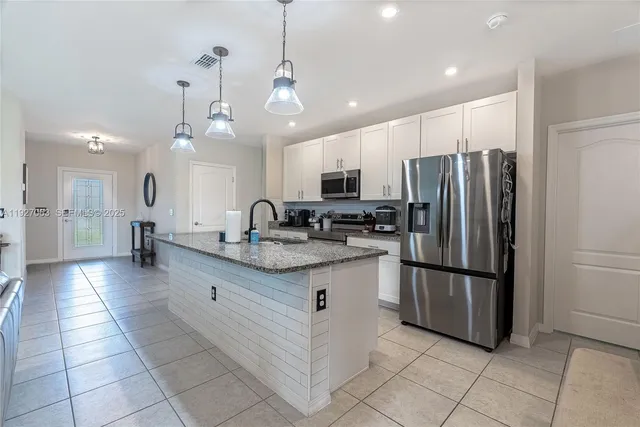a kitchen with stainless steel appliances granite countertop a refrigerator and a sink
