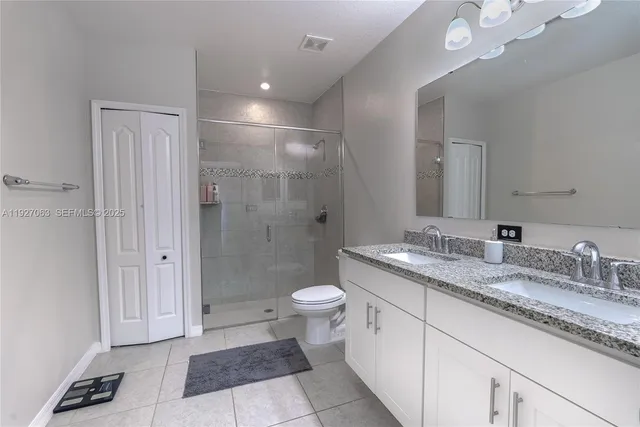 a bathroom with a granite countertop sink a toilet a mirror and shower