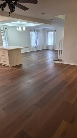 a view of empty room with kitchen and window