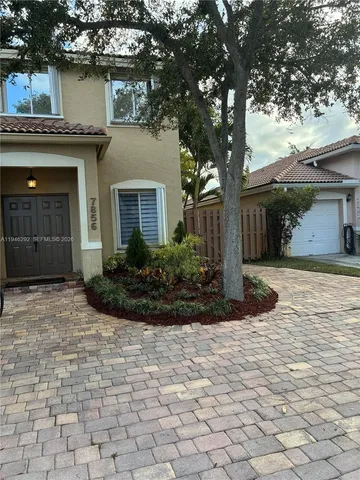 a front view of a house with a yard and potted plants
