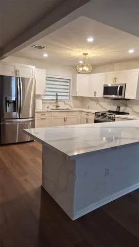 a large kitchen with kitchen island a sink stove and refrigerator