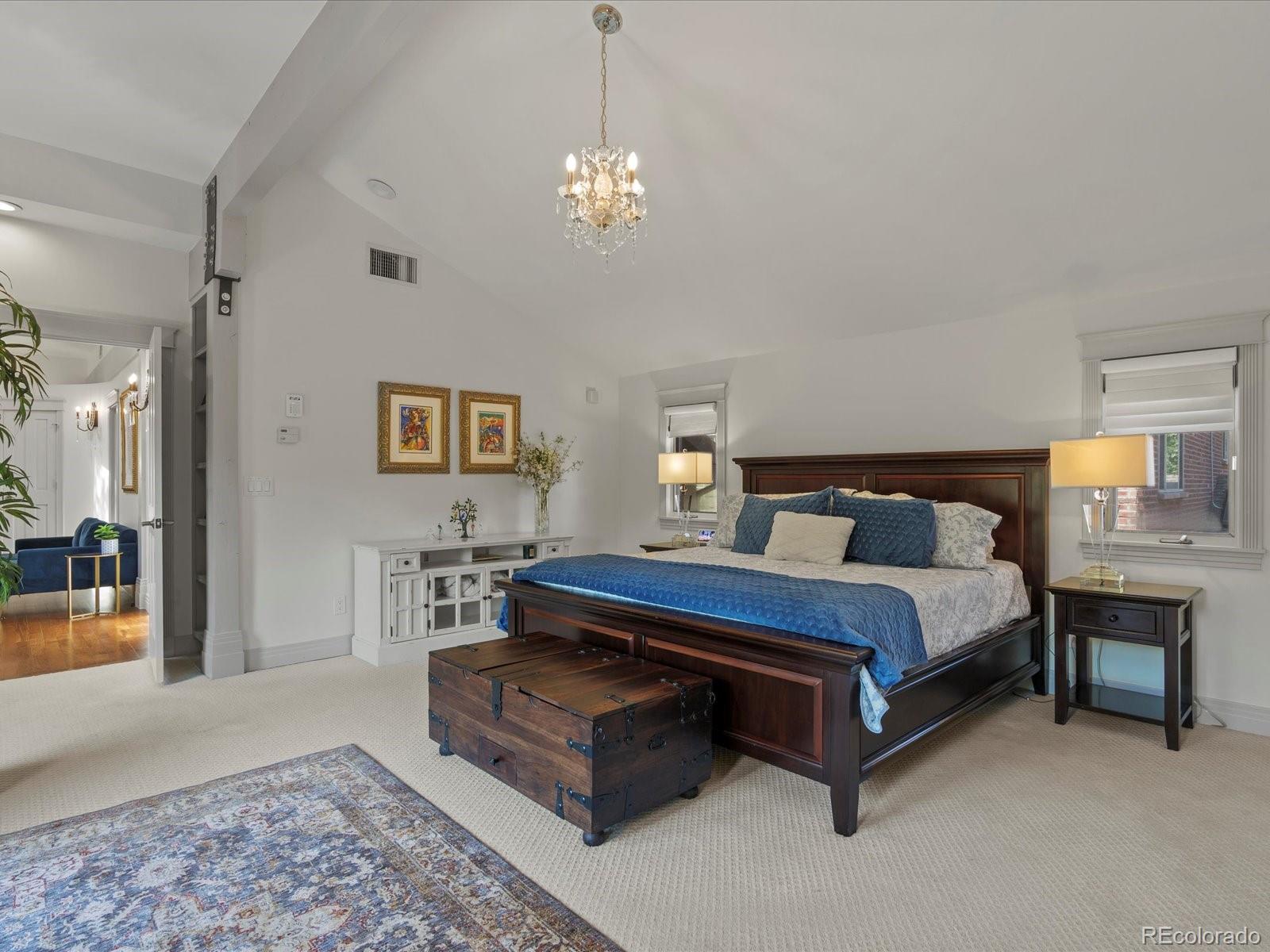 718 North Locust Street Denver, CO 80220 - Photo 20 of 46 a spacious bedroom with a bed a chandelier and mirror