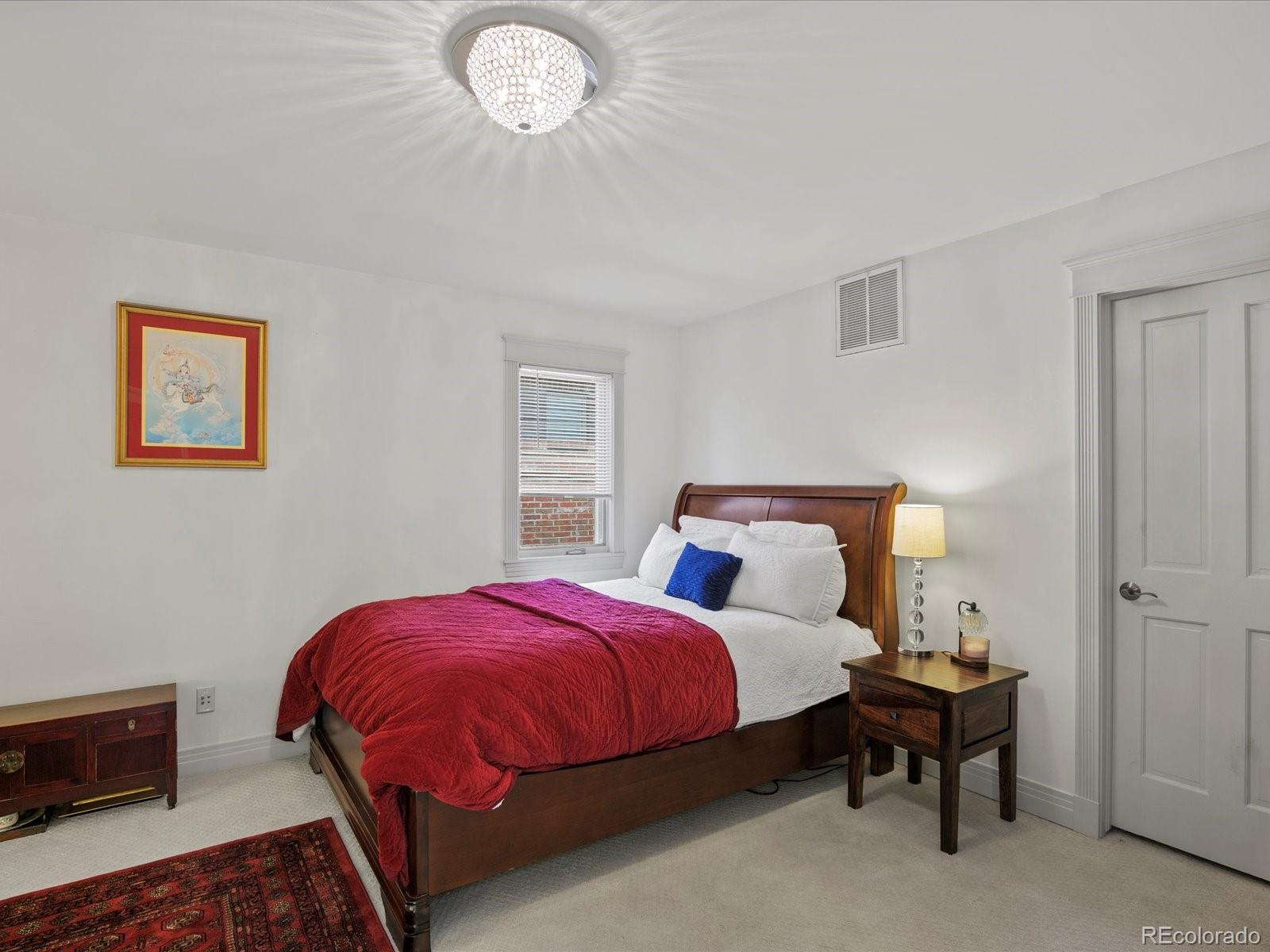 718 North Locust Street Denver, CO 80220 - Photo 30 of 46 a spacious bedroom with a bed and a chandelier