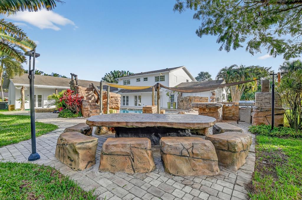 8233 Stagecoach Lane Boca Raton, FL 33496 - Photo 81 of 88 a view of a patio with table and chairs potted plants and palm tree