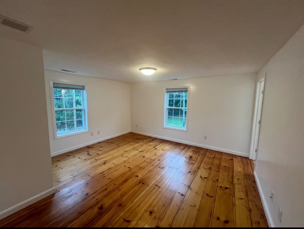 265 Dunstable Road, Unit 1 Tyngsborough, MA 01879 - Photo 3 of 6 an empty room with wooden floor and windows