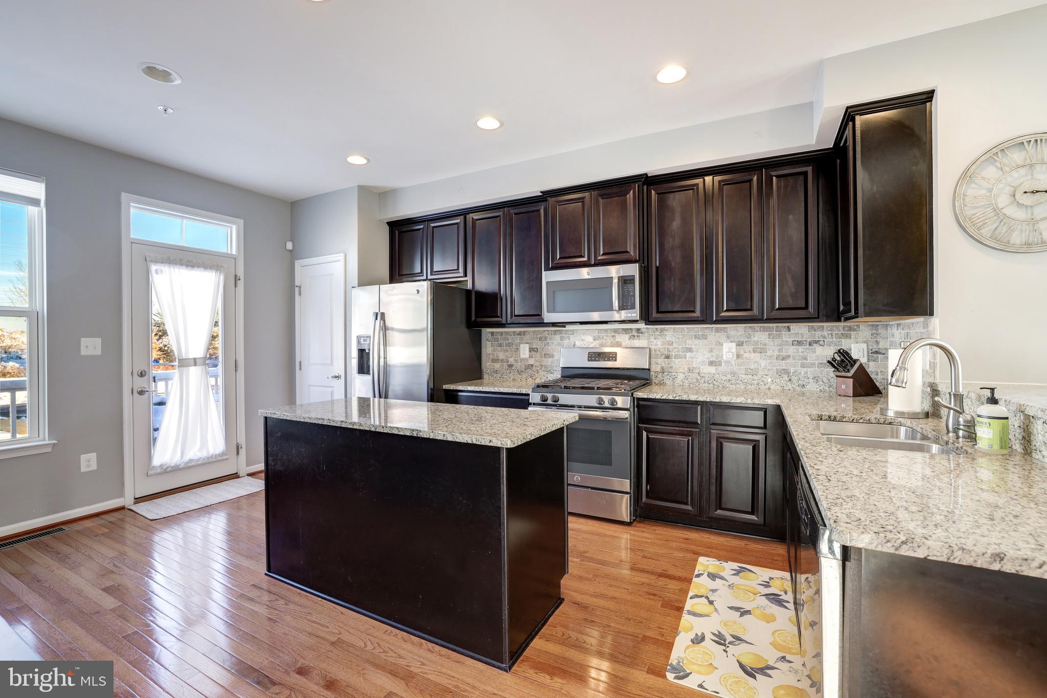 24845 Coats Square Aldie, VA 20105 - Photo 13 of 40 a kitchen with kitchen island granite countertop wooden cabinets a sink dishwasher and a stove with wooden floor