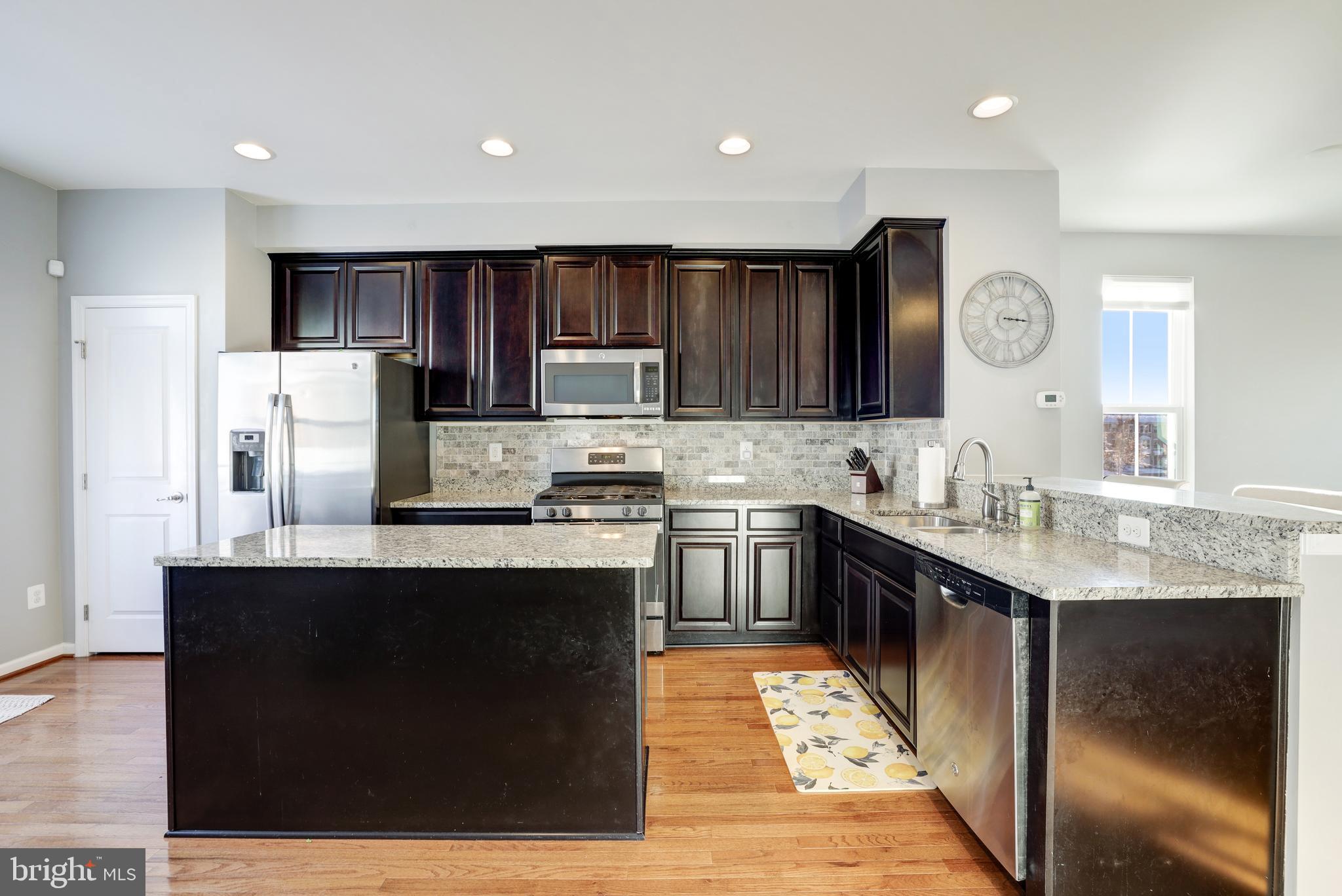 24845 Coats Square Aldie, VA 20105 - Photo 14 of 40 a kitchen with kitchen island granite countertop a sink stove and refrigerator