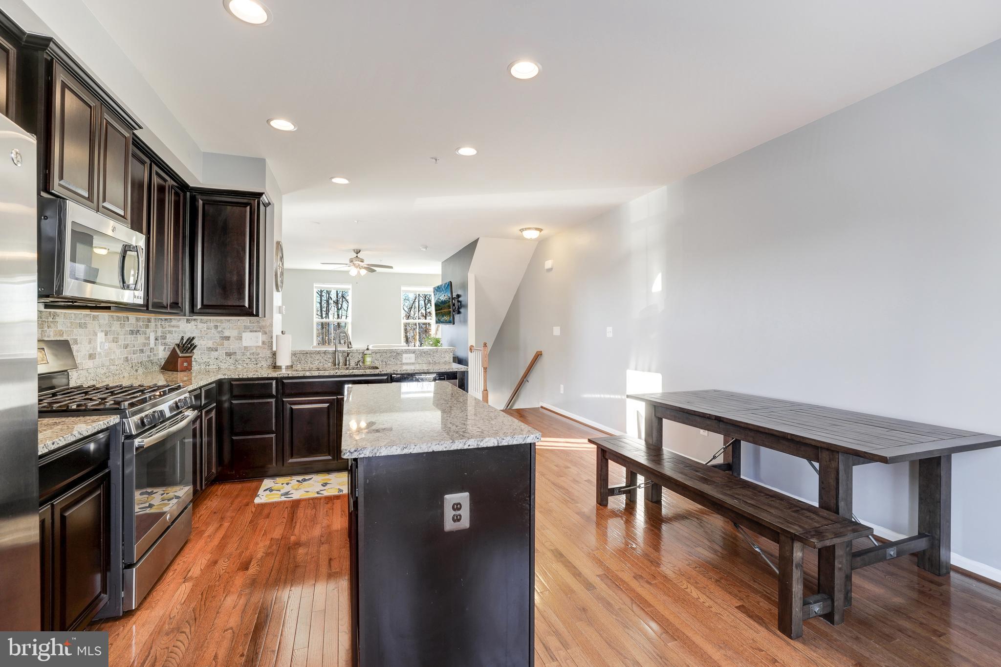 24845 Coats Square Aldie, VA 20105 - Photo 15 of 40 a kitchen with stainless steel appliances granite countertop a refrigerator a stove top oven a sink dishwasher and chairs with wooden floor