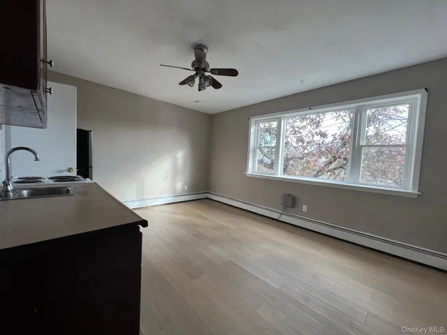 a view of an empty room with a window and wooden floor
