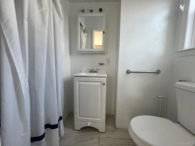 a bathroom with a sink a toilet a window and vanity