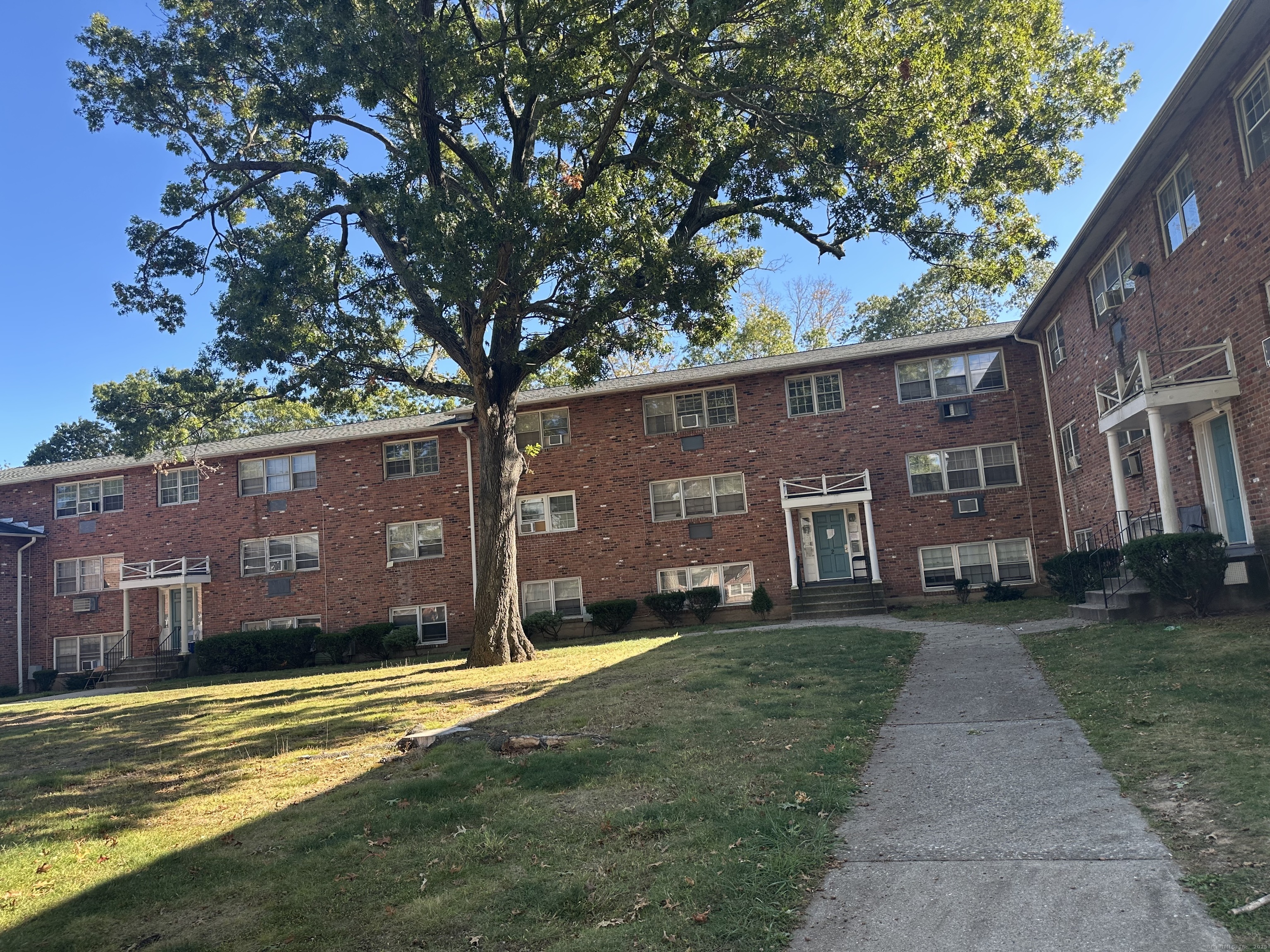 5 Treat Street, Unit 2A West Haven, CT 06516 - Photo 2 of 15 a view of a brick building next to a yard with large trees