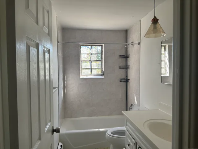 a bathroom with a granite countertop bathtub sink vanity mirror and toilet
