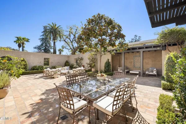 a view of a patio with couches table and chairs under an umbrella with a fire pit