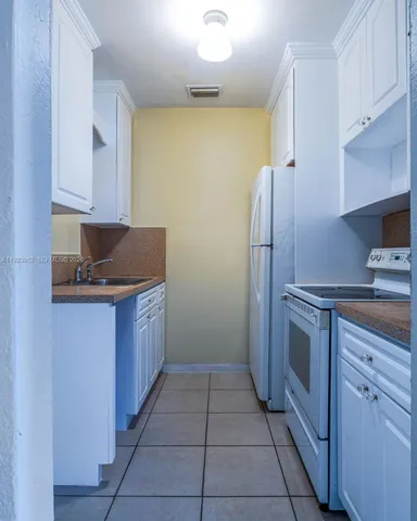 a kitchen with a refrigerator sink and cabinets