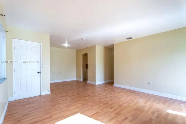 a view of an empty room with wooden floor