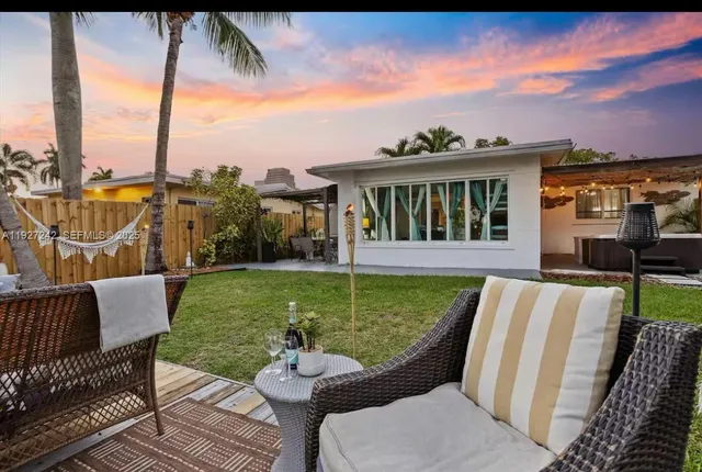 a view of a patio with couches chairs potted plants and a palm tree