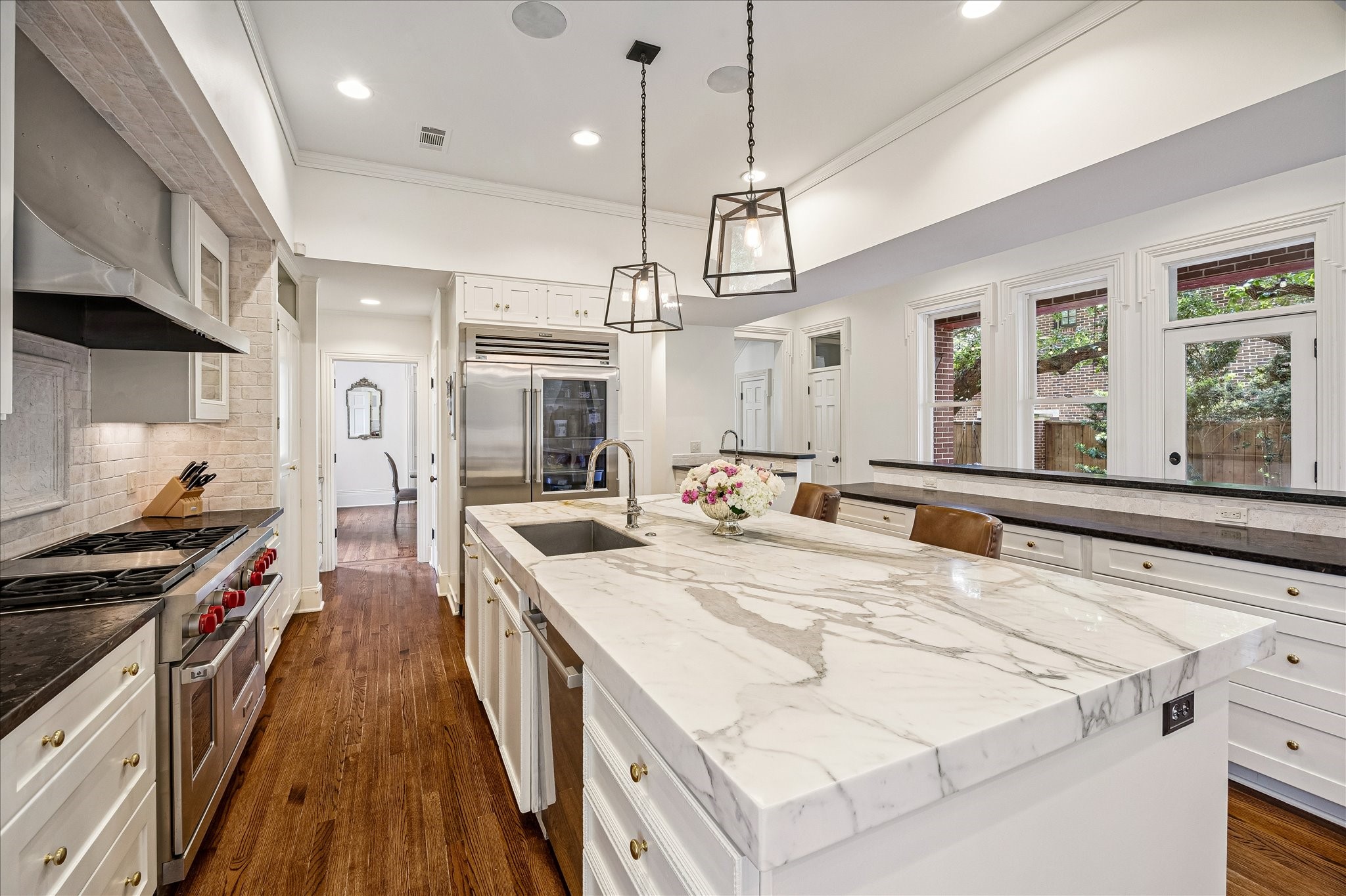 2368 Timber Lane Houston, TX 77027 - Photo 13 of 46 Designed to accommodate everything from elevated entertaining to intimate family gatherings, the open-concept kitchen blends striking design with exceptional functionality. Rich black leathered countertops contrast beautifully against a dramatic 9-foot Calacatta marble island with seating, while a separate 9-foot serving counter with additional storage enhances both flow and convenience. Rear access to the kitchen allows for discreet catering entry.