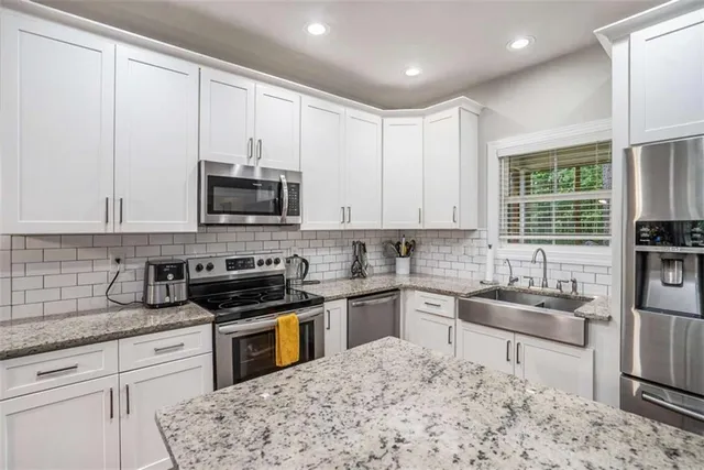 a kitchen with stainless steel appliances granite countertop a stove a sink and a microwave