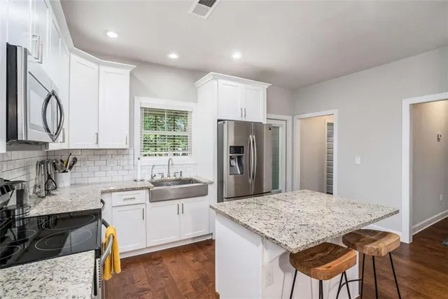 a kitchen with stainless steel appliances granite countertop a sink refrigerator and cabinets
