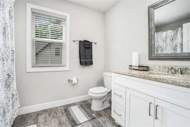a bathroom with a granite countertop toilet sink and mirror
