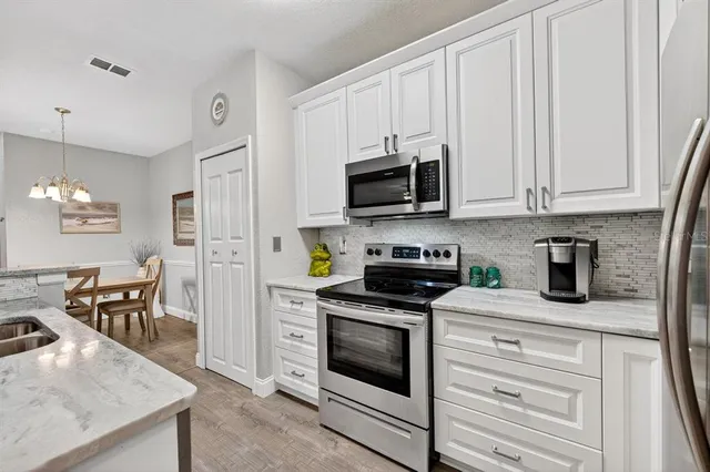 a kitchen with granite countertop a sink stainless steel appliances and white cabinets