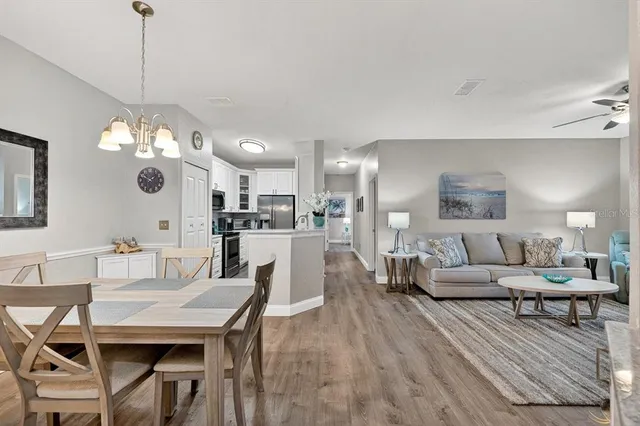 a living room with furniture kitchen view and a chandelier