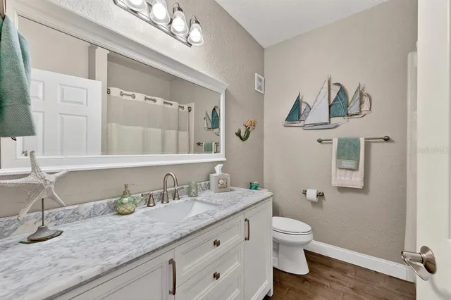a bathroom with a granite countertop toilet sink and mirror