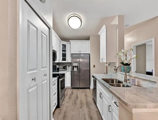 a kitchen with stainless steel appliances granite countertop a refrigerator a stove and a sink with wooden floor