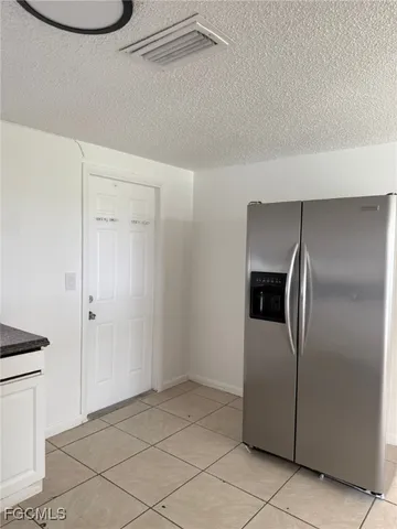 a view of a refrigerator in kitchen and an empty room