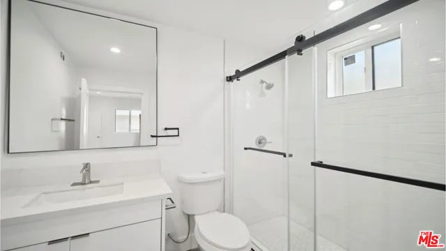 a bathroom with a toilet sink vanity granite and shower