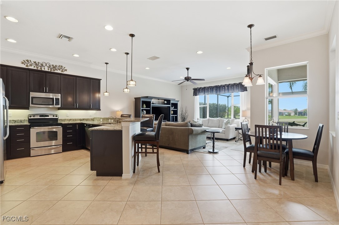 20604 Chestnut Ridge Drive North Fort Myers, FL 33917 - Photo 9 of 49 a kitchen with stainless steel appliances granite countertop a stove a sink a microwave a dining table and chairs