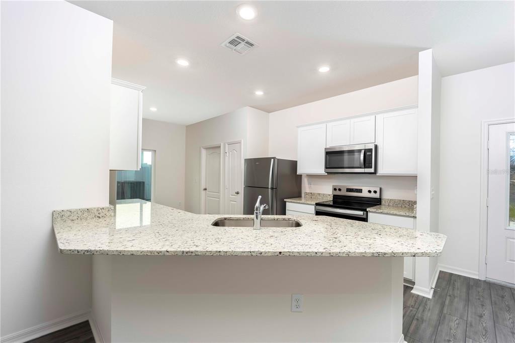 13486 Leaping Water Way Astatula, FL 34705 - Photo 9 of 20 a kitchen with stainless steel appliances granite countertop a sink refrigerator and microwave