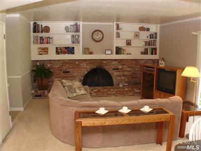 Formal family room features built-in book cases over a large brick fireplace. Covered patio is located just off cameral to the right.