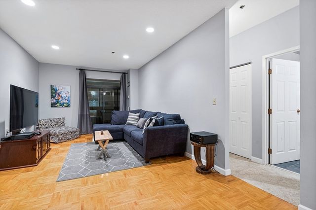a living room with furniture a flat screen tv and a refrigerator