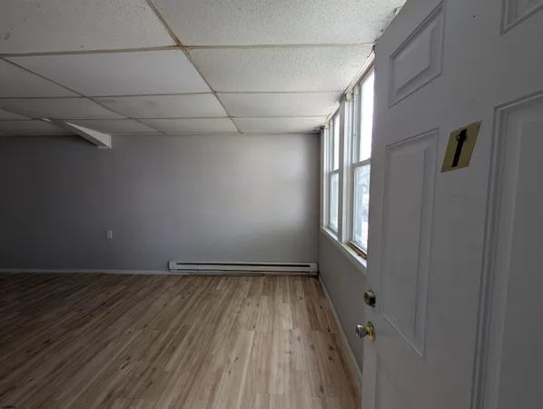 a view of an empty room with a window and wooden floor