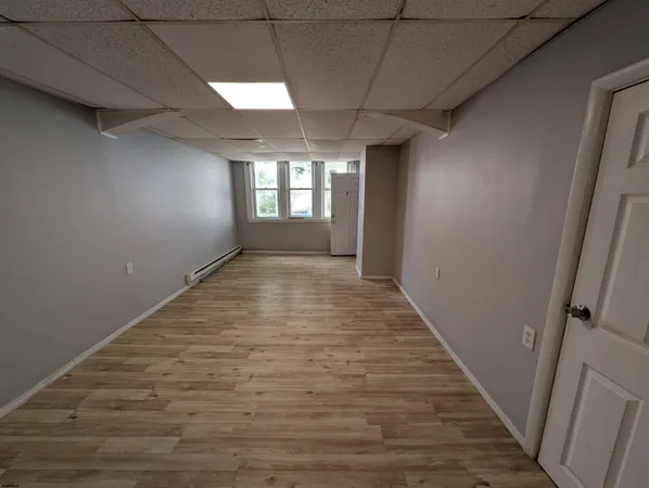 a view of hallway with window and wooden floor